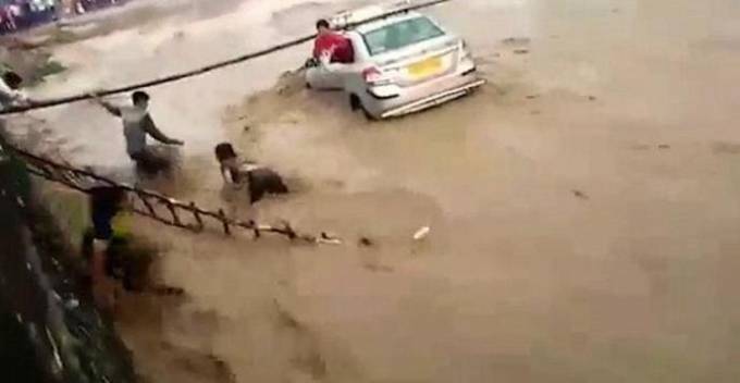 Драматический момент спасения индийской пары из автомобиля, смытого течением реки, запечатлели очевидцы происшествия