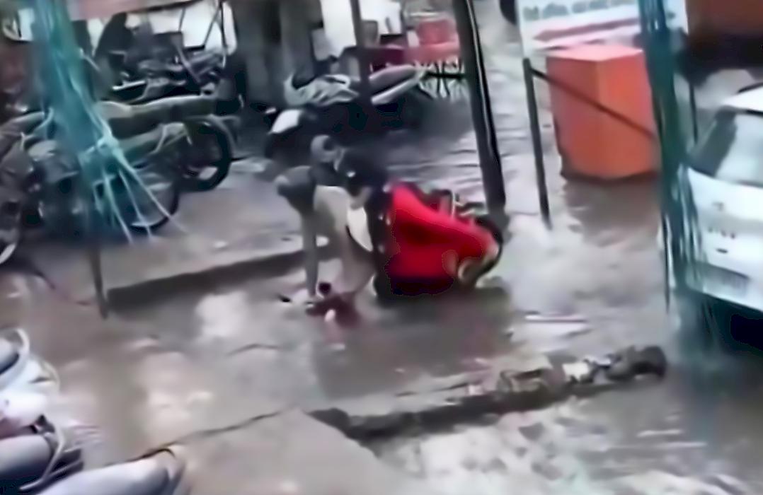 Полицейский с женой на скутере неудачно проверили глубину затопленной канавы в Индии